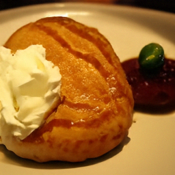 Pixel sample for: A round, golden-brown pastry with visible spiral layers sits on a white plate, d